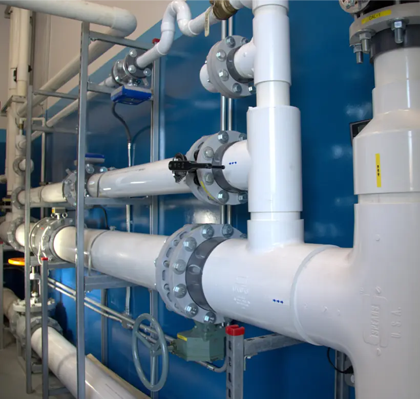 White PVC flow-test loop against the blue lab wall